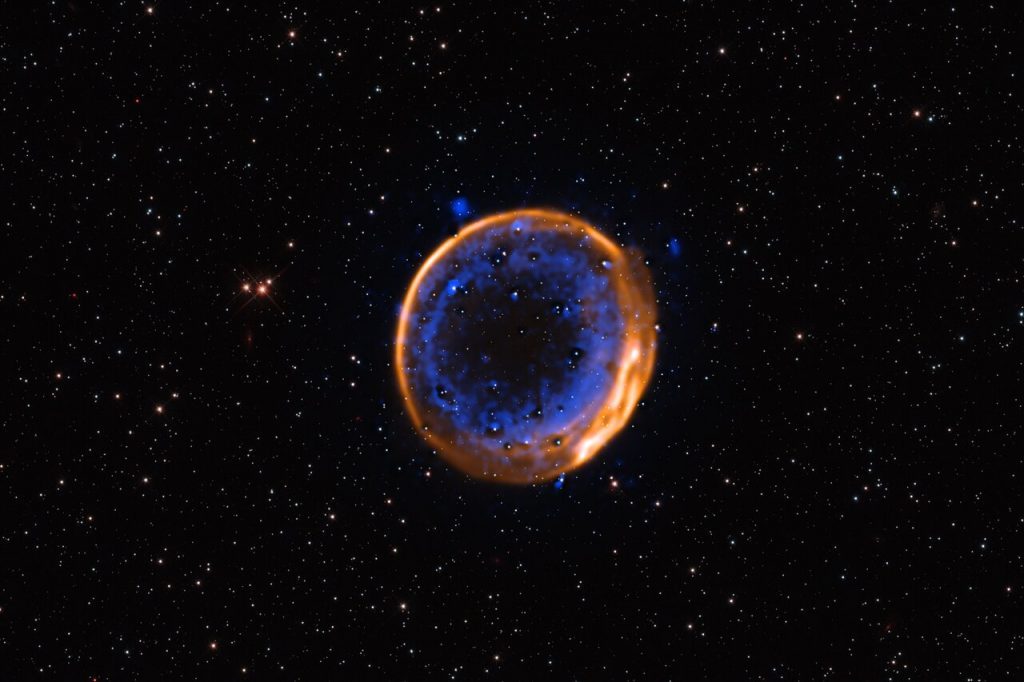 This image, taken with ESO’s Very Large Telescope (VLT), shows the supernova remnant SNR 0509-67.5. These are the expanding remains of a star that exploded hundreds of years ago in a double-detonation – the first photographic evidence that stars can die with two blasts. The data were captured with the Multi-Unit Spectroscopic Explorer (MUSE) instrument at the VLT. MUSE allows astronomers to map the distribution of different chemical elements, displayed here in different colours. Calcium is shown in blue, and it is arranged in two concentric shells. These two layers indicate that the now-dead star exploded with a double-detonation.